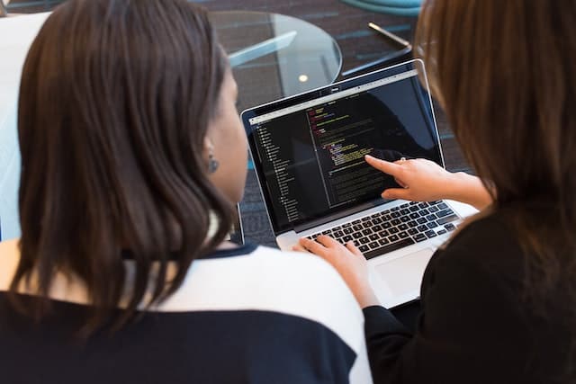 A web developer is writing code in a laptop